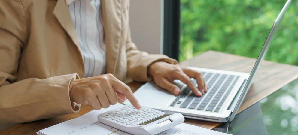 Person working on laptop and calculator